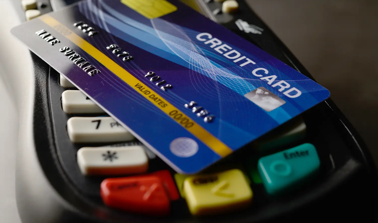 An image of a credit card and credit card reader, being used by a consumer at a point of sale